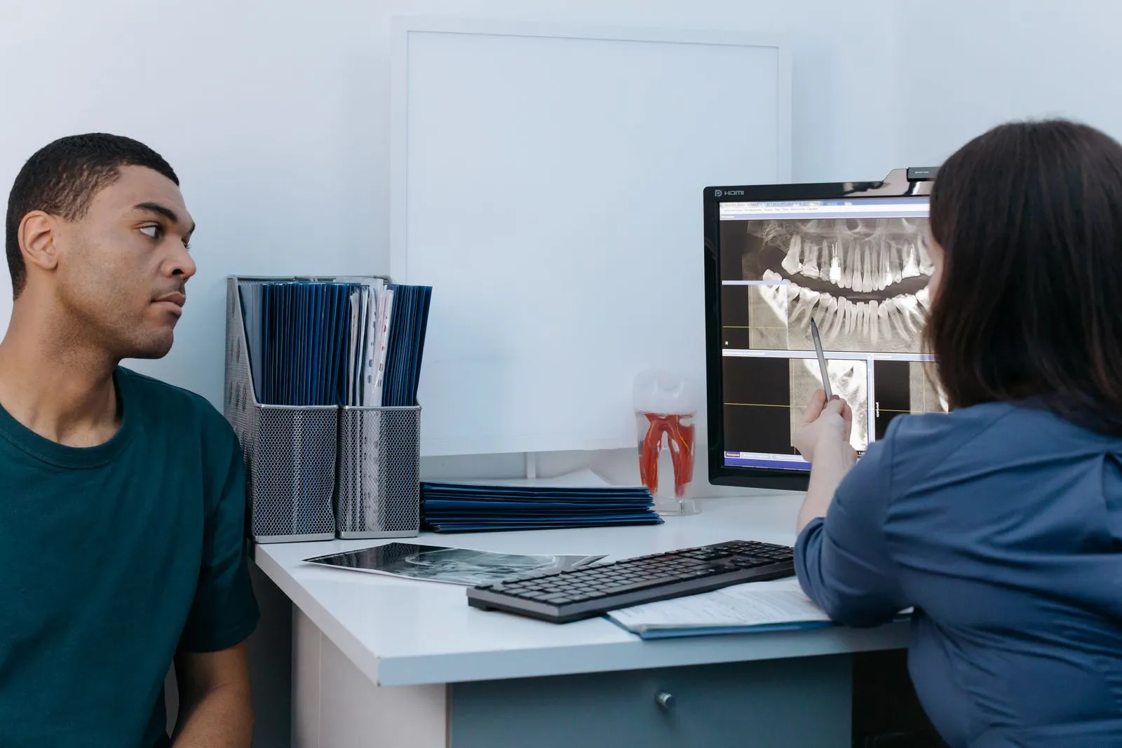 A dental professional and a patient reviewing a dental X-ray